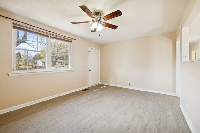 a view of kitchen and empty room with wooden floor