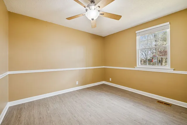 an empty room with a window and a fan