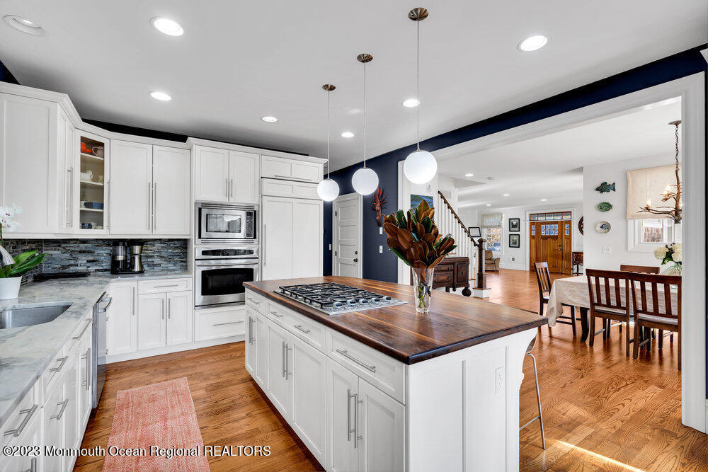 405 Brown Street Brielle, NJ 08730 - Photo 19 of 92 a kitchen with stainless steel appliances granite countertop a stove top oven a sink a dining table and chairs with wooden floor
