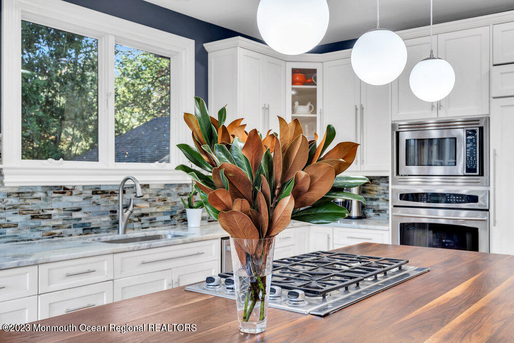 405 Brown Street Brielle, NJ 08730 - Photo 22 of 92 a kitchen with stainless steel appliances granite countertop a stove a sink a microwave a dining table and chair