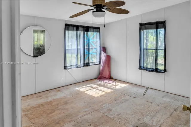 an empty room with windows and fan