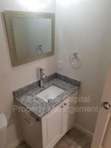 a bathroom with a granite countertop sink and a mirror
