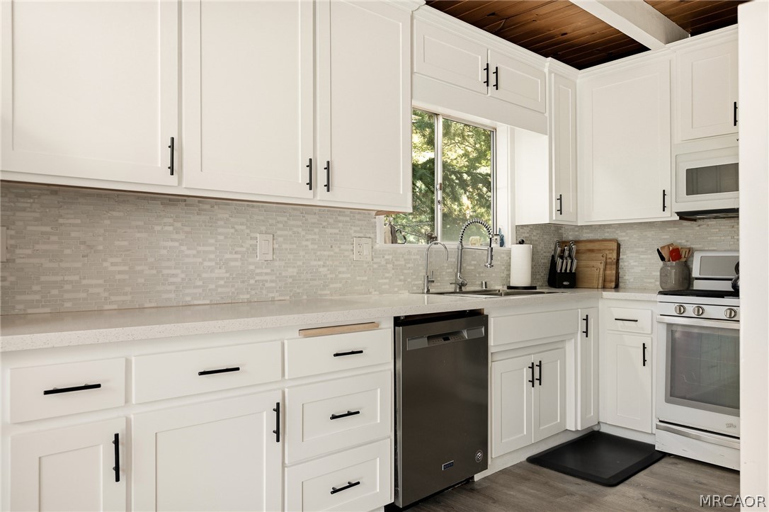 316 Pioneer Road Lake Arrowhead, CA 92352 - Photo 7 of 35 a kitchen with stainless steel appliances granite countertop white cabinets a sink and dishwasher with wooden floor