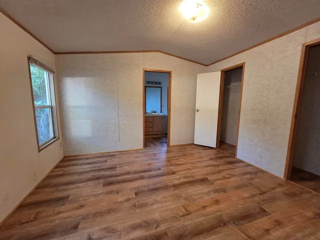 a view of an empty room with window and wooden floor