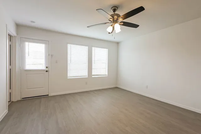 an empty room with a window and a fan