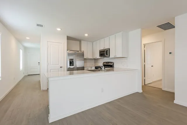 a kitchen with stainless steel appliances granite countertop a refrigerator sink and white cabinets
