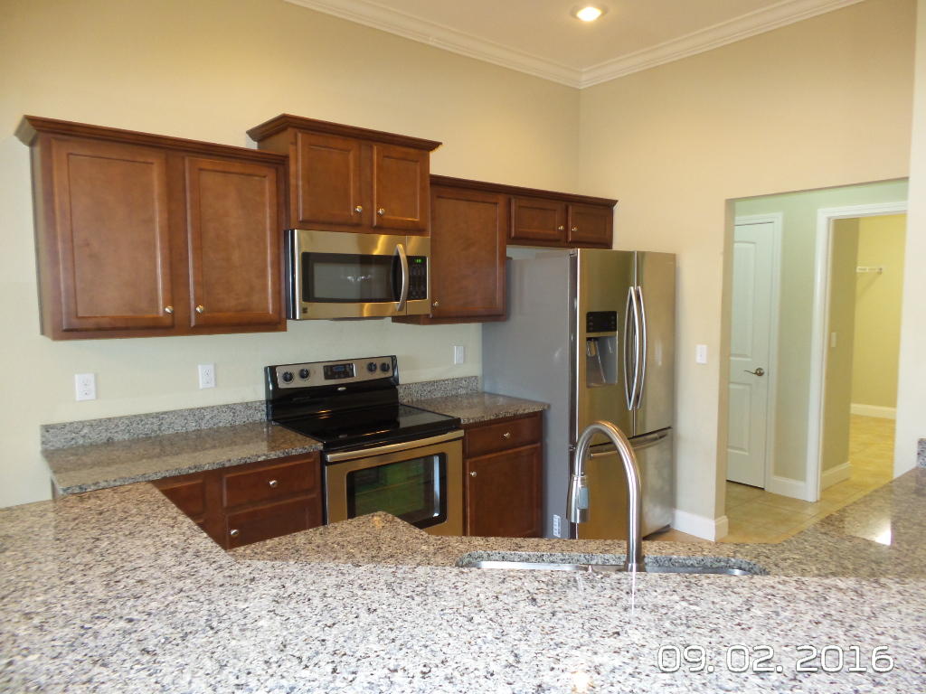 4589 Hermosa Road Crestview, FL 32539 - Photo 9 of 21 a kitchen with granite countertop wooden cabinets a refrigerator and a sink
