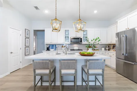 a kitchen with stainless steel appliances a dining table chairs refrigerator and sink