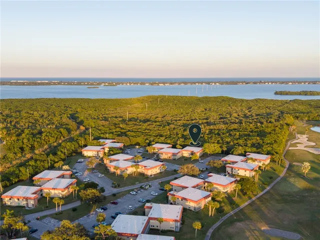 an aerial view of ocean and residential houses with outdoor space