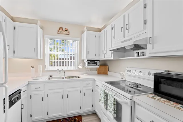 a kitchen with cabinets appliances a sink and a window