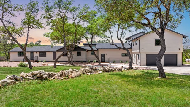 a front view of a house with a garden and trees
