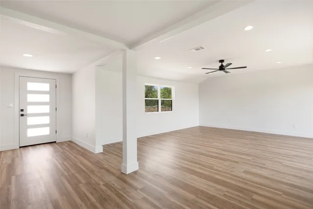 an empty room with wooden floor cabinet and windows
