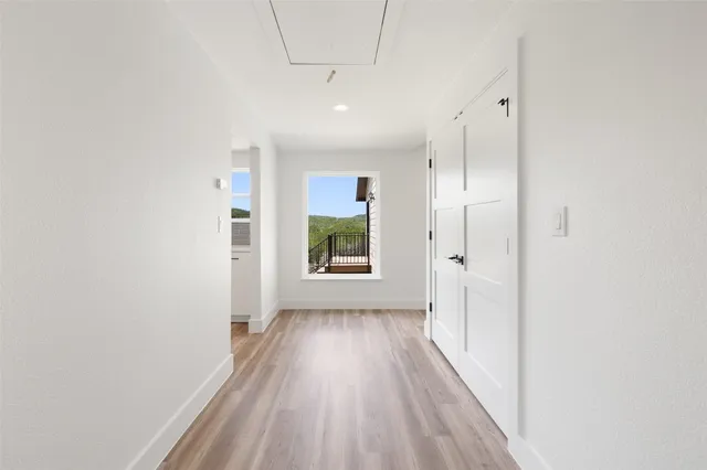 a view of a hallway with wooden floor and a window