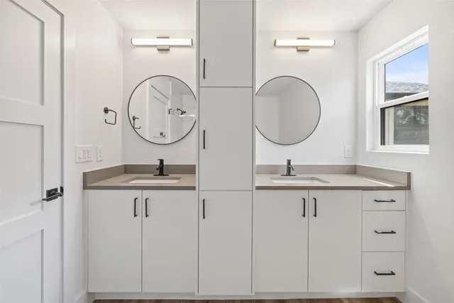 a bathroom with a granite countertop double vanity sink and a mirror
