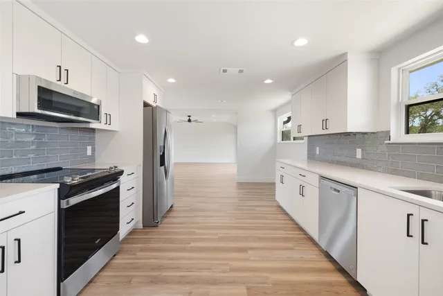 a large kitchen with stainless steel appliances granite countertop a stove a sink and a refrigerator