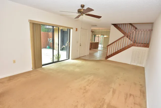 a view of an empty room with wooden floor and a ceiling fan