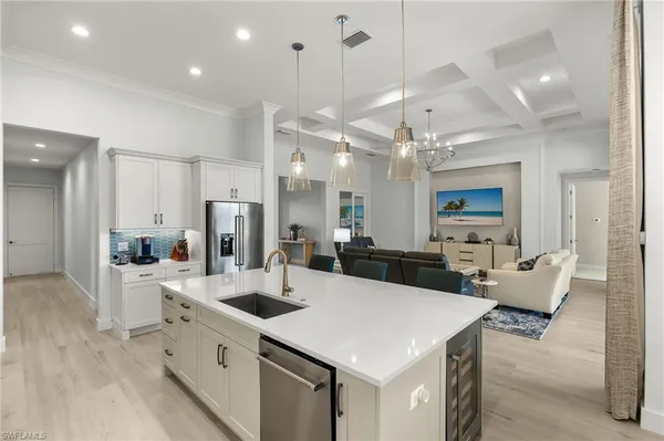 a large kitchen with kitchen island a white counter space a sink appliances and living room view