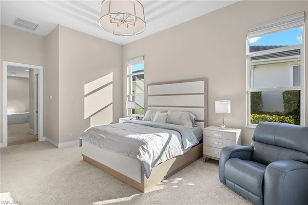 a bedroom with a bed couch and windows