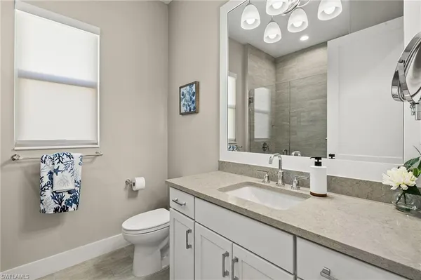 a bathroom with a granite countertop sink mirror vanity and toilet