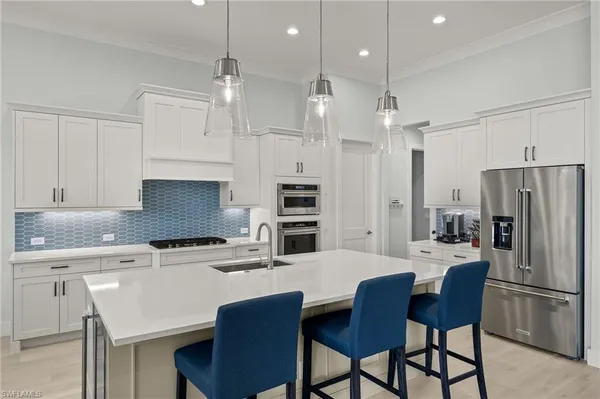 a kitchen with stainless steel appliances a refrigerator a stove a sink a dining table and chairs