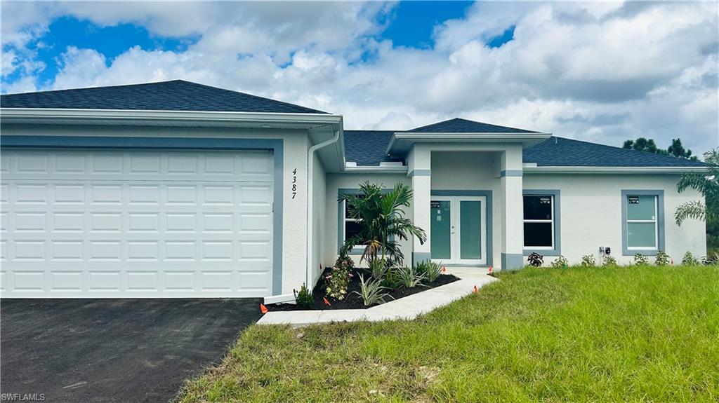a view of a house with small yard plants and a large tree
