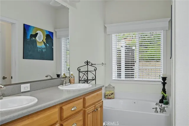 a bathroom with a granite countertop sink a mirror a window and a bathtub