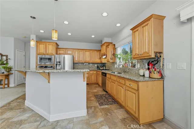 a kitchen with stainless steel appliances granite countertop a sink and a refrigerator