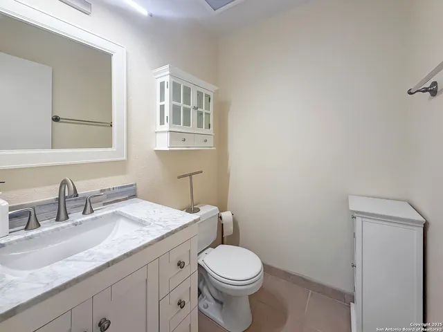 a bathroom with a granite countertop toilet sink and mirror