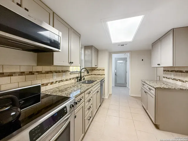a large kitchen with stainless steel appliances granite countertop a stove and a sink