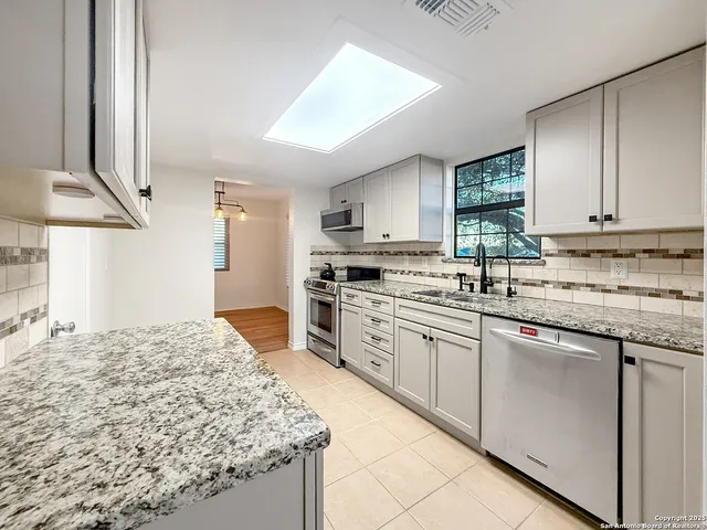 a kitchen with stainless steel appliances granite countertop a stove a sink and a microwave