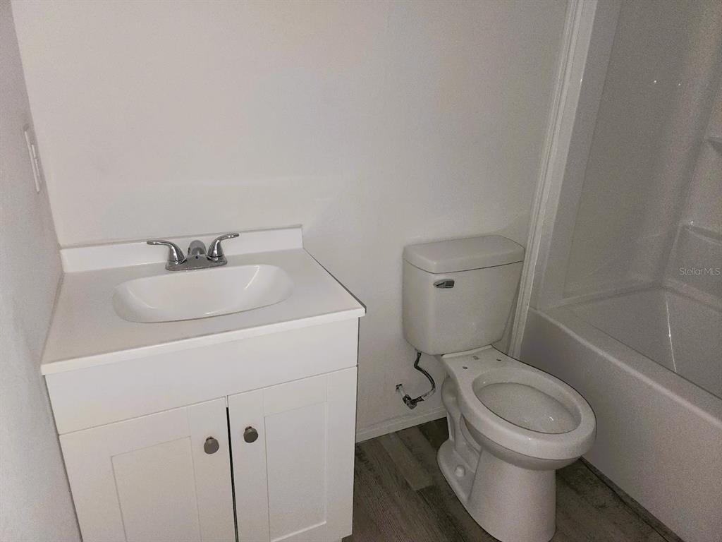 3114 Holly Hill Cutoff Road Davenport, FL 33837 - Photo 9 of 12 a white toilet sitting next to a bathroom sink and vanity