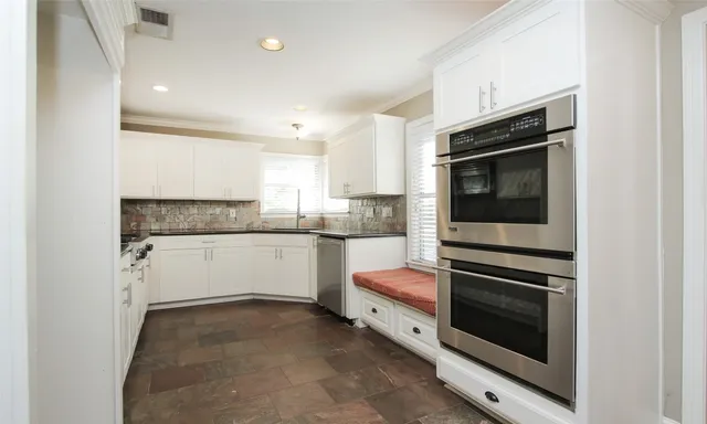 a kitchen with granite countertop white cabinets and stainless steel appliances