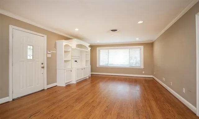 a view of an empty room with wooden floor and window