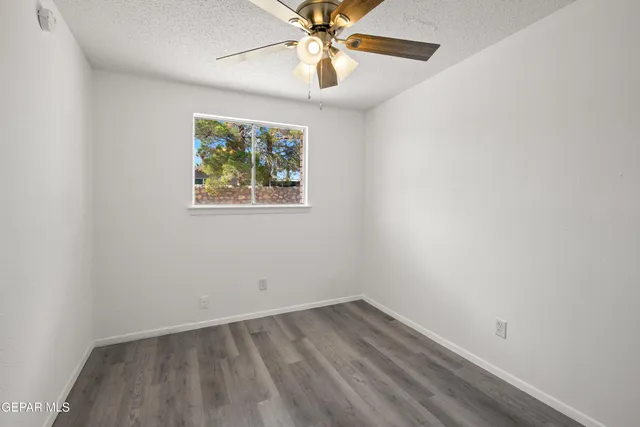 an empty room with a window and a fan