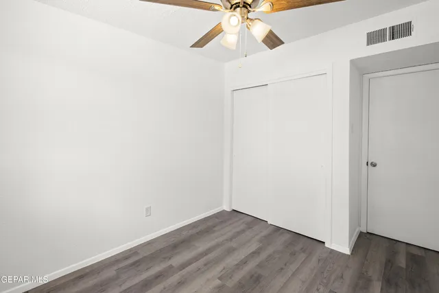 an empty room with wooden floor ceiling fan and table