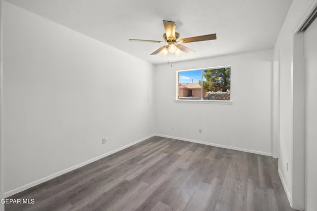 an empty room with windows and fan