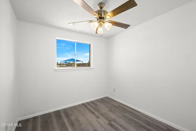 an empty room with a window and a ceiling fan