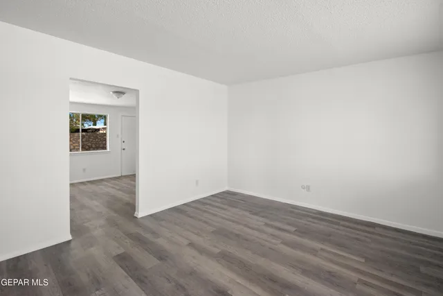 an empty room with wooden floor & windows