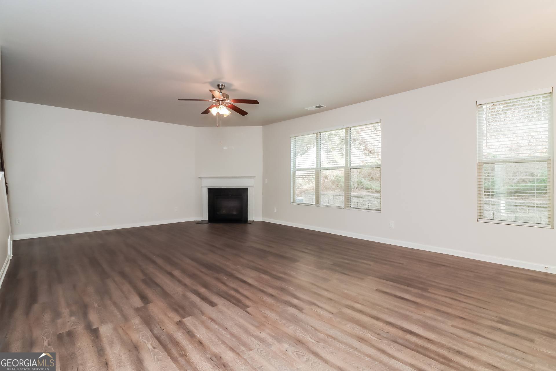 194 Randy Way Dallas, GA 30132 - Photo 2 of 17 an empty room with wooden floor chandelier fan and windows