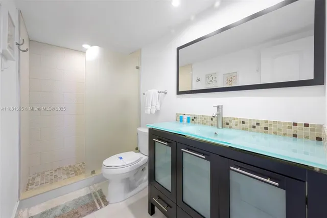 a bathroom with a granite countertop sink mirror vanity and toilet