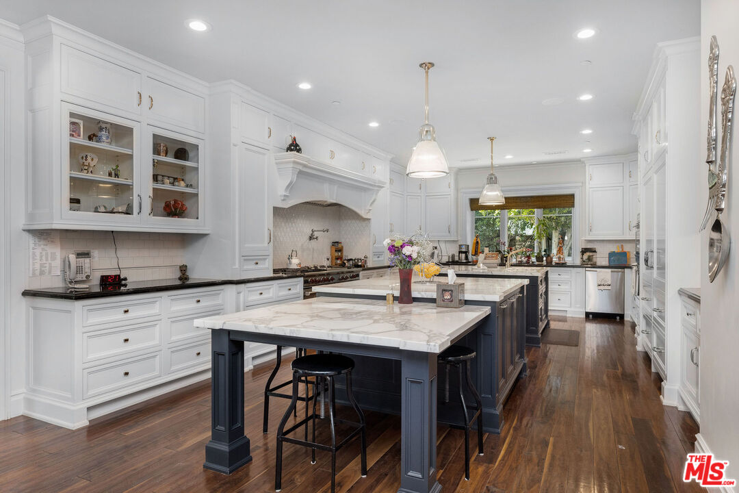 23924 Long Valley Road Hidden Hills, CA 91302 - Photo 12 of 46 a kitchen with stainless steel appliances granite countertop a kitchen island a stove a table and chairs in it