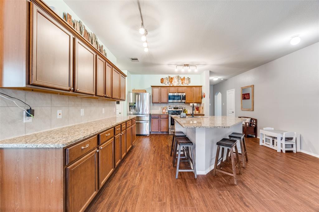 1011 Riverstone Trail Princeton, TX 75407 - Photo 7 of 26 a kitchen with stainless steel appliances granite countertop wooden floors a stove and a center island