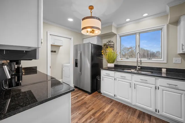 a kitchen with granite countertop a stove a refrigerator and a sink with wooden floor