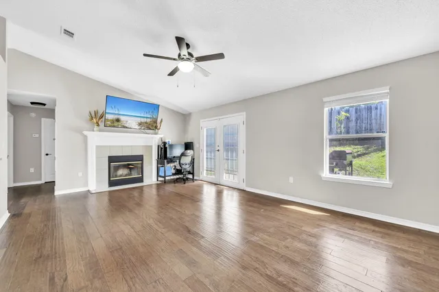 an empty room with windows fireplace and a ceiling fan