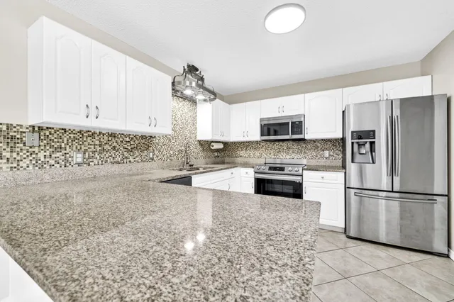 a kitchen with granite countertop a stove a sink and a refrigerator