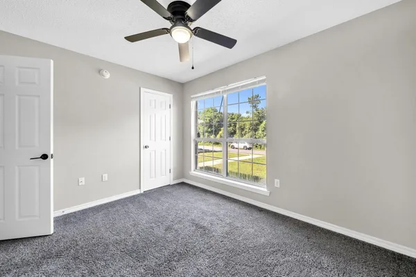 an empty room with chandelier fan and windows