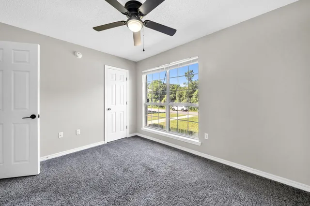 an empty room with chandelier fan and windows