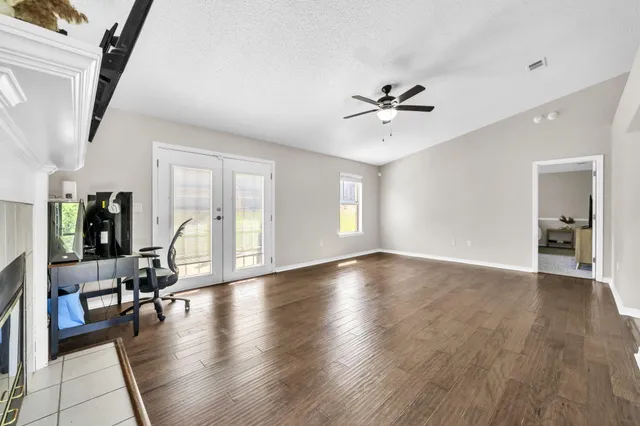 a view of an empty room with a fireplace and wooden floor