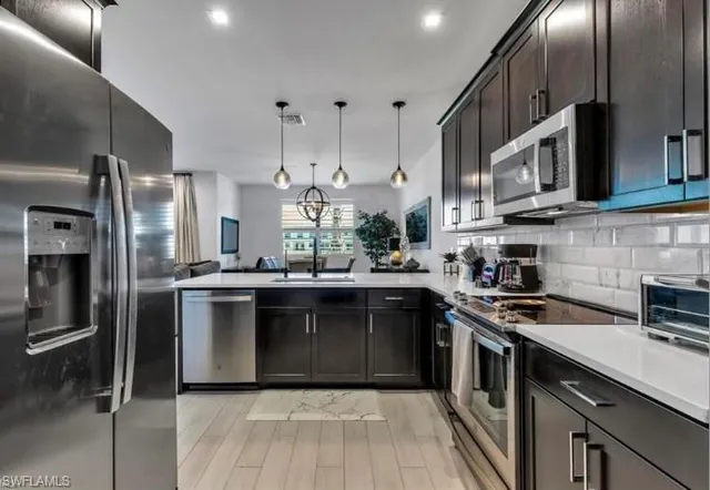a kitchen with stainless steel appliances granite countertop a sink a stove a refrigerator and cabinets