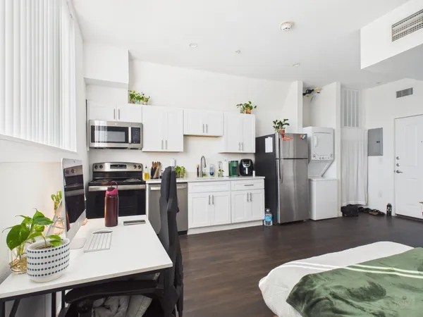 a kitchen with stainless steel appliances a refrigerator a stove a sink dishwasher and white cabinets with wooden floor